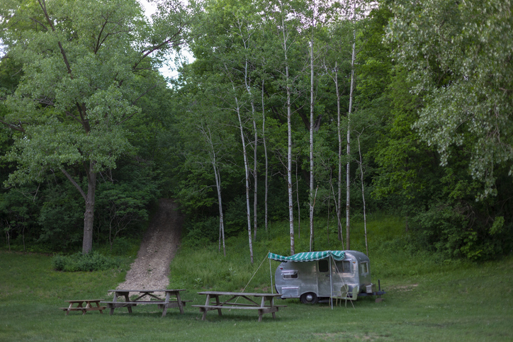 Vintage camper sits near the forest.