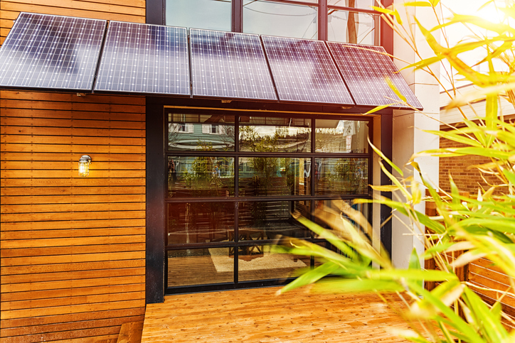Photo of a modern home exterior with a solar power awning over the back porch